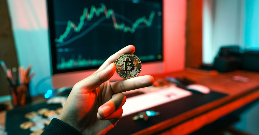 man håller bitcoin framför datorskärm